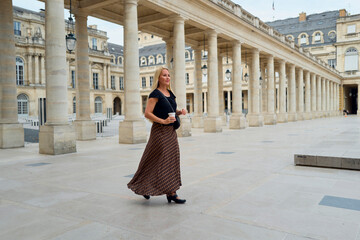 Obraz premium Blonde woman with coffee walks through Paris courtyard