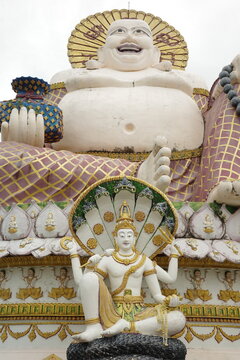 Ornate Laughing Buddha and multi armed deity statues at a temple