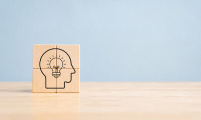 New ideas, creativity and innovative thinking concept. Wooden blocks arranged to form a head silhouette with a lightbulb inside, symbolizing ideas, creativity and innovative thinking. © mystockworkc