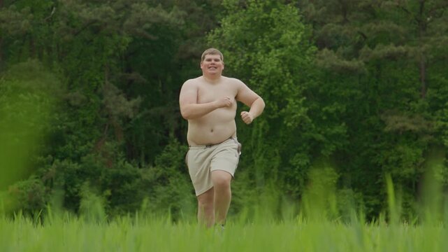 Running man trains outdoors. Overweight running shows struggle. Park running workout concept. Running supports fat body transformation.