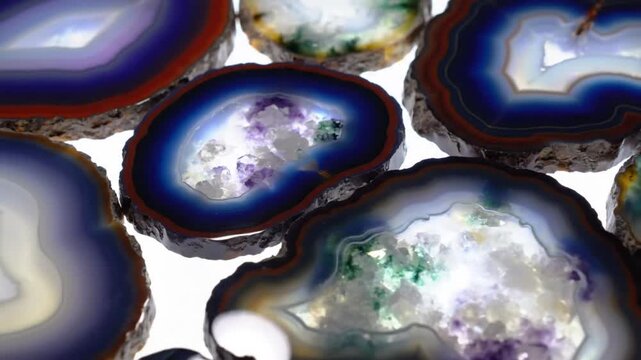 Mesmerizing close up view of colorful illuminated agate crystal slices with unique geological patterns.