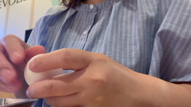 ゆで卵の殻をむく女性