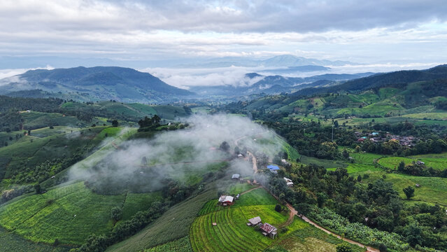 Aerial landscape view of rice terrace and wooden huts in mountains on cloudy morning