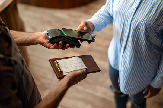 Customer using cashless mobile payment technology for a quick bill transaction in cafe