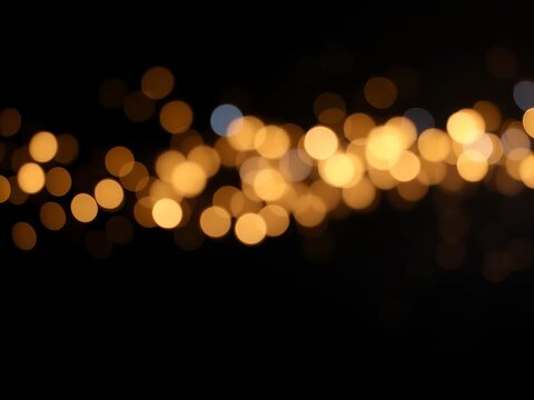 Faintly glowing, abstract lights dance across a dark background, with hints of gold, blue, and black, subtly blurred to create a sense of depth, de-focused, black