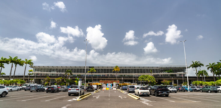 Les Abymes, Guadeloupe - July 19, 2026: Exterior view of Pointe-a-Pitre International Airport main terminal building with parking lot under a cloudy sky.