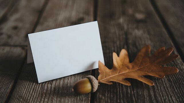 Blank greeting card with autumn leaves and acorns on rustic wooden table