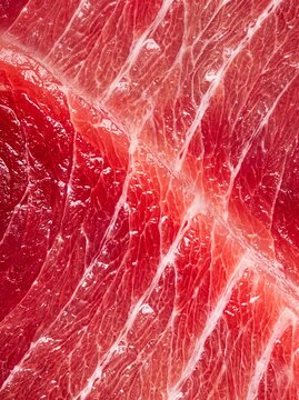 Extreme close-up of raw red meat texture with white fat marbling and muscle fibers