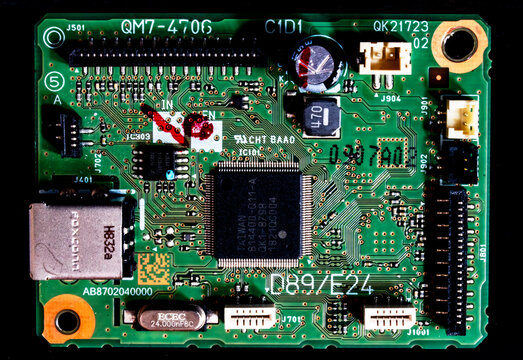Detailed close-up of a green printed circuit board featuring branded microchips, surface-mount components, and text markings.