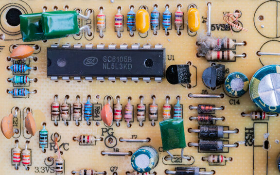 Detailed close-up of a yellow printed circuit board featuring a branded microchip, resistors, and capacitors.