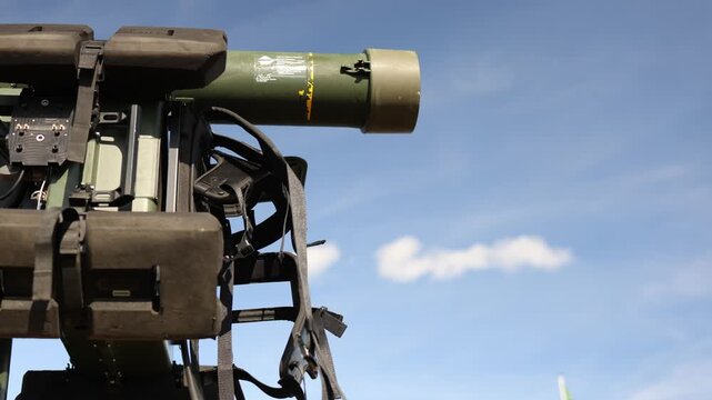Military missile launcher with guided weapon tube and electronic control equipment stands outdoors against clear blue sky during modern defense system field display exercise