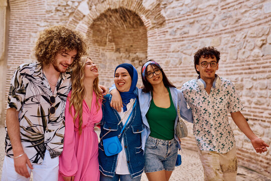 Diverse Group Of Friends Laughing Together While Exploring Historic City Streets On A Sunny Day