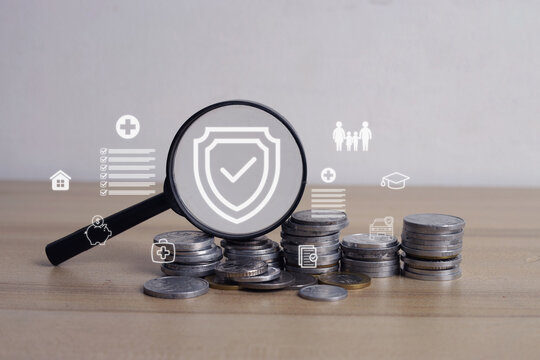 Closeup of Stacks Coins Under Magnifying Glass Displaying Insurance Shield Hologram