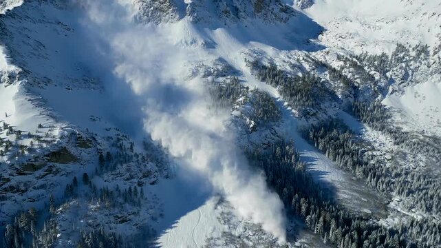 Breathtaking aerial video of snowy mountain wilderness, cascading avalanche clouds, raw winter alpine terrain and dramatic landscape