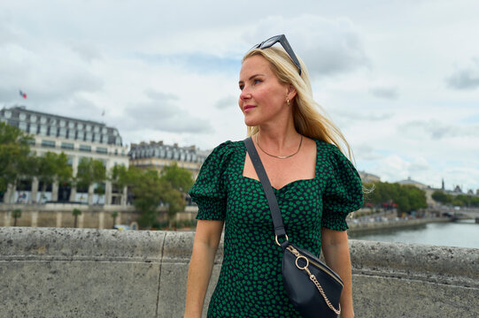 Blonde woman in a green dress exploring the city of Paris