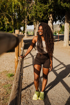 Happy woman with long braids walking on a sunny park path