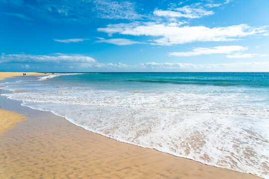 Waves washing onto a golden sand beach on a sunny day