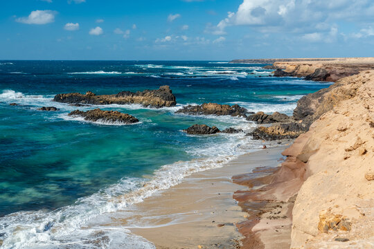 Rugged coastline with turquoise water and sandy beach on a sunny day