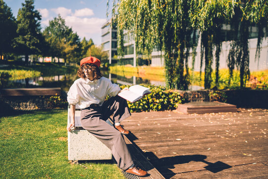 A stylish young woman enjoys a book in a city park