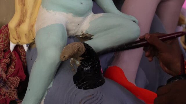 artisan hand painting a traditional clay idol