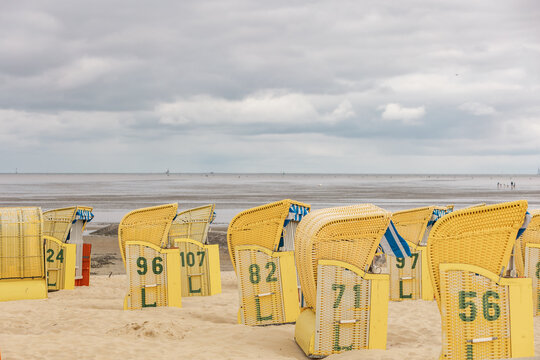 Yellow woven beach baskets stand on the sandy beach near the sea
