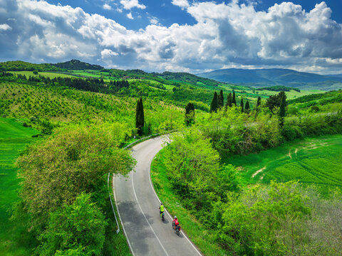 Man and woman cycle on a rural road in Tuscany