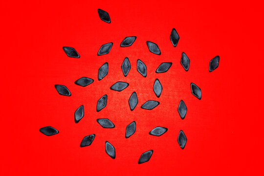 Black salty licorice candy scatters across a bright red background