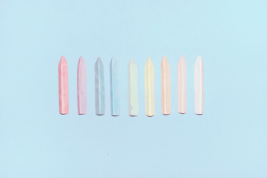 Row of colorful pastel crayons on a light blue background