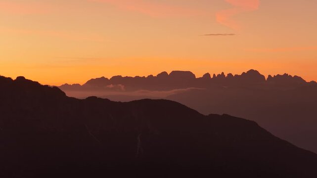 Sunset over dramatic Dolomite mountain silhouettes and layered