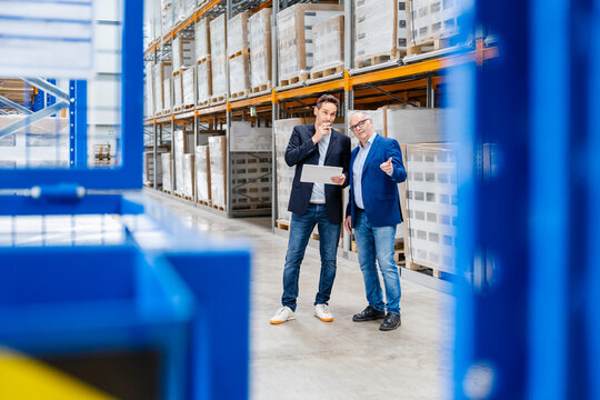 Managers discuss logistics with a tablet in a large warehouse
