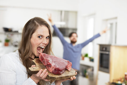 Happy young womanpretending to bite into raw steak