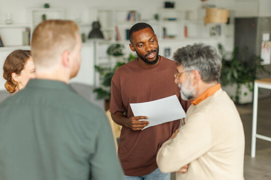 A businessman discusses a document with a colleague at the office