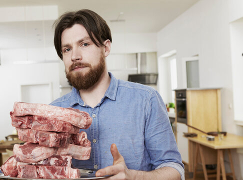 Man in kitchen with raw steaks