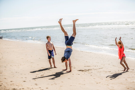 Netherlands, Zandvoort, father with two children doing a handstand on the beach