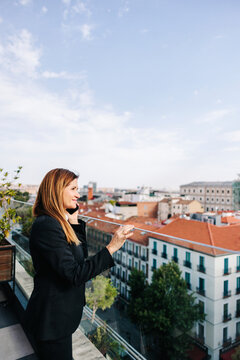 Businesswoman talks on phone at Madrid rooftop terrace