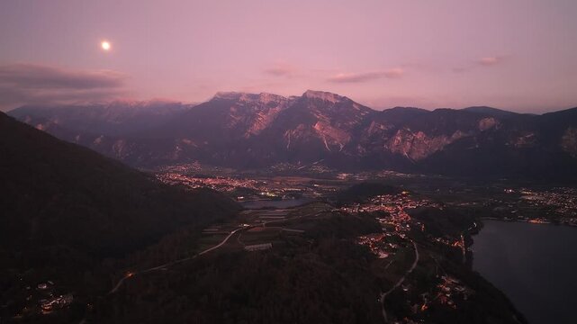 Lake Levico and illuminated alpine villages beneath rugged