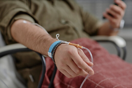 Unrecognizable hand with IV drip receiving therapy at clinic