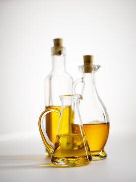 Three glass bottles of golden olive oil on a white background