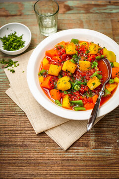 Tomato vegetable stew with polenta croutons on a wooden table