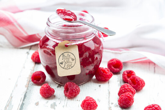 Spoon and jar of raspberry jam and raspberries