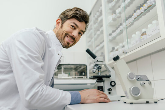 Portrait of smiling man using microscope in laboratory