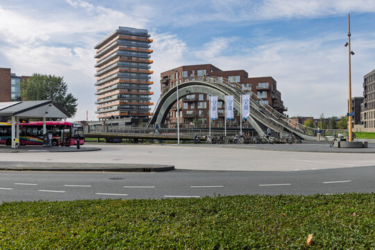 Purmerend, Netherlands - September 27, 2026: View of the modern Melkwegbrug arched pedestrian bridge, a bus stop, and contemporary residential high-rise buildings in the city.