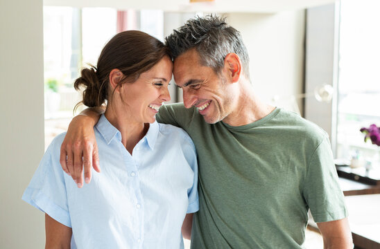 A smiling man and woman share an embrace indoors