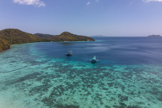 Boats float over a tropical coral reef in Coron Palawan Philippines