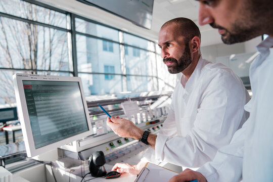 Male scientist pointing at computer monitor in hightech laboratory