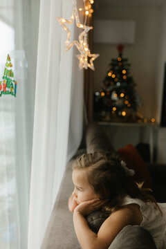 A girl looks out the window waiting for Santa Claus at Christmas