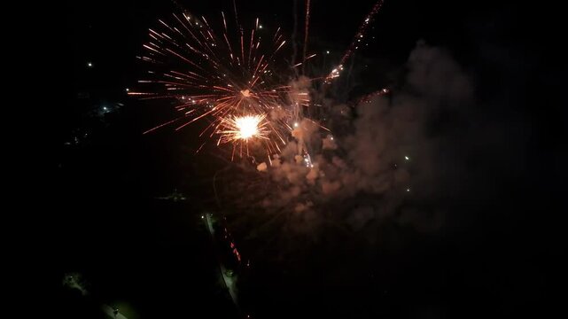 Fireworks exploding in the night sky with orange sparks and smoke