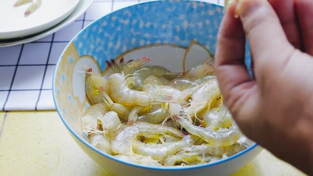 Hands Peeling Raw Shrimp in a Blue Bowl for Cooking