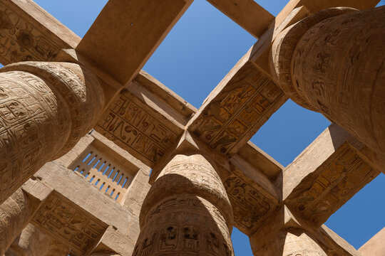 Carved temple columns and stone lintels frame a clear blue sky in Egypt