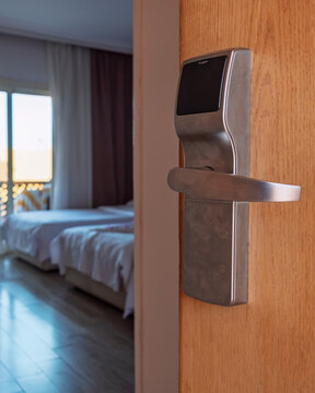 Old hotel room with twin beds seen through an open wooden door, showing dated interior